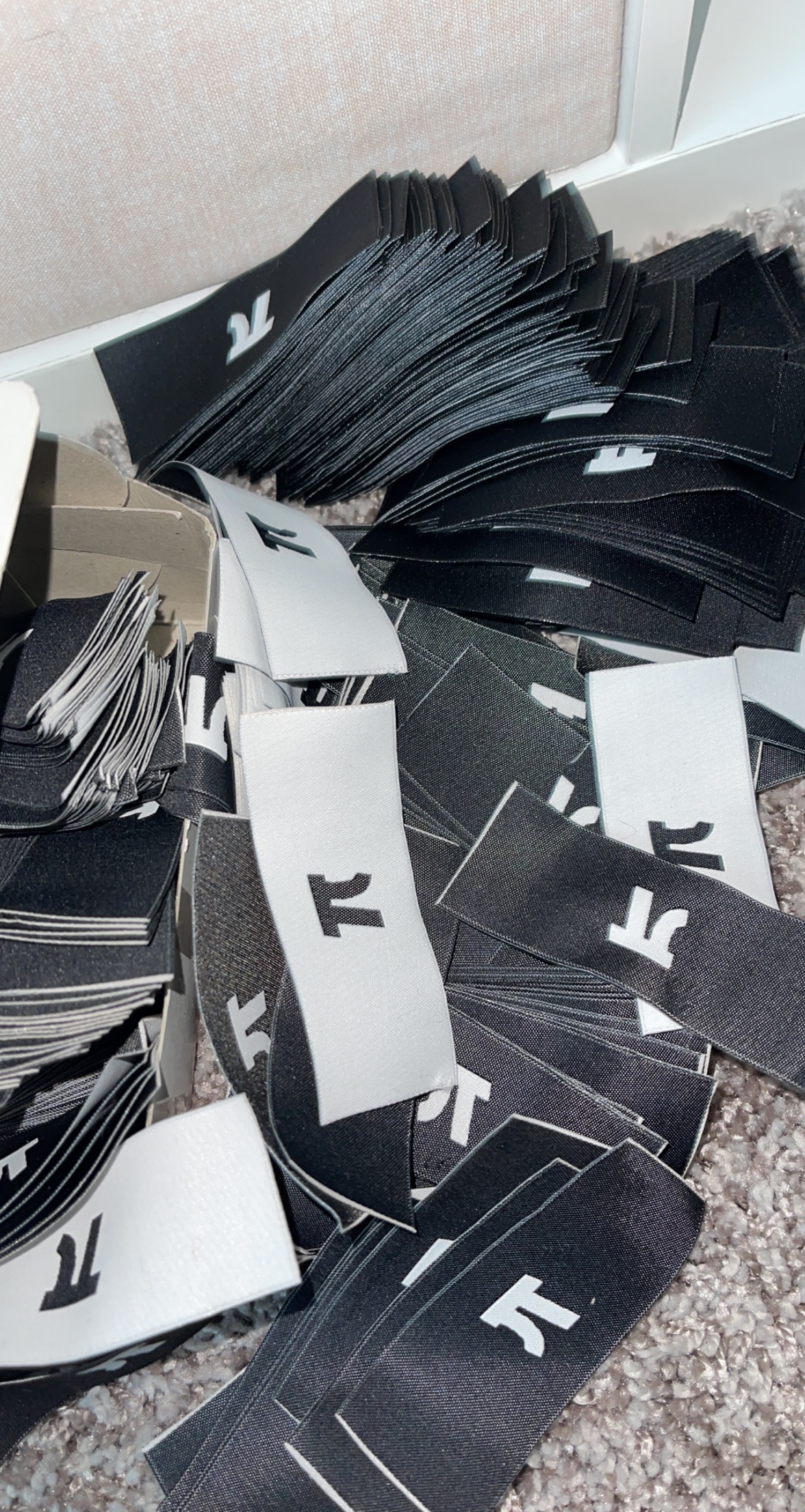 Stacks of black and white woven labels prepared for finishing.