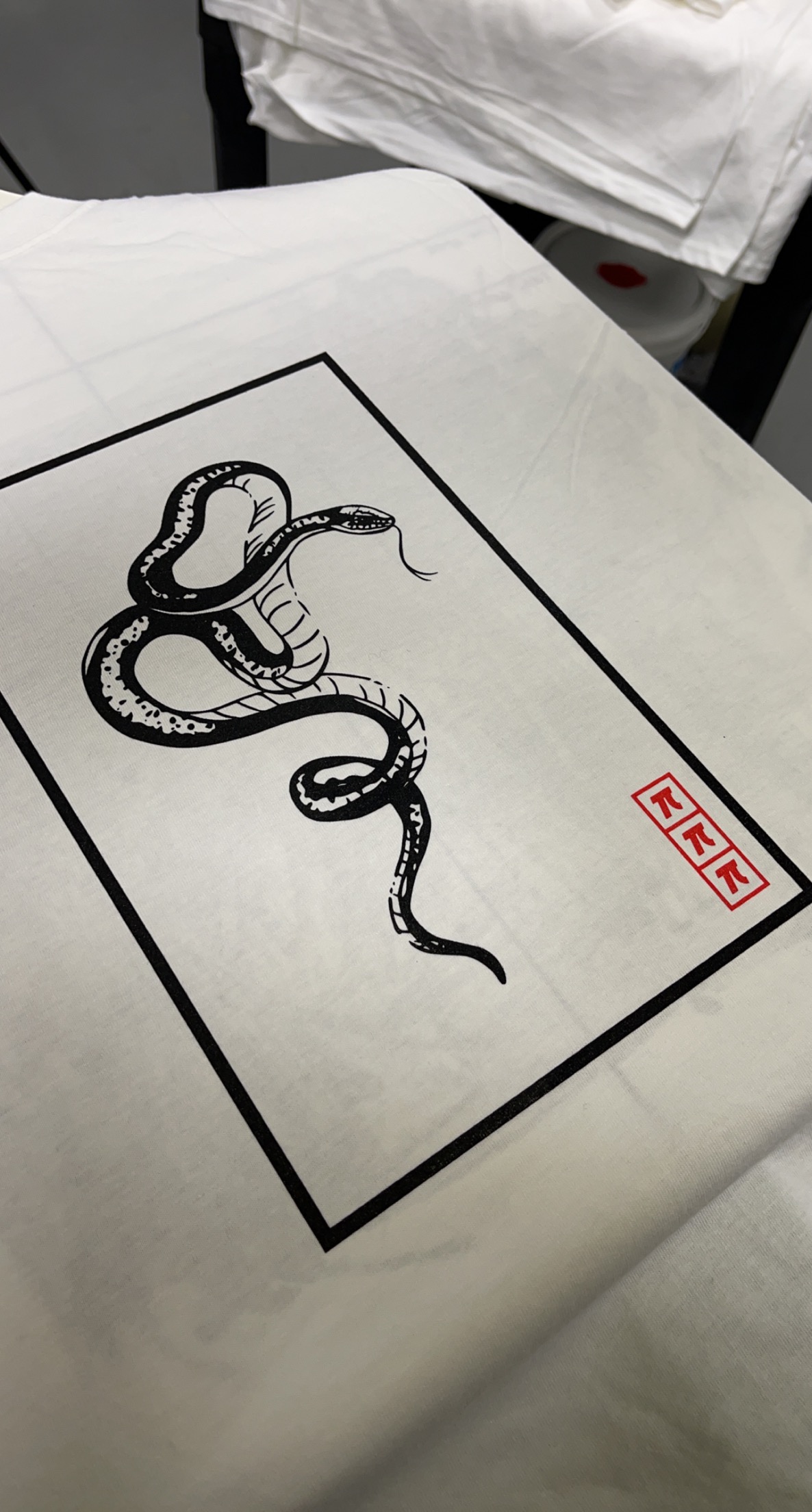 Close detail of printed snake artwork on a white garment.